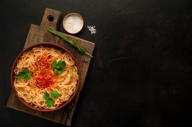koyu taş arka plan üzerinde domates sosu ve maydanoz yaprakları ile İtalyan spagetti makarna