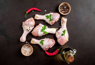 Baharat, biber ve maydanoz yaprakları ile tavuk bacakları siyah taş arka plan üzerinde