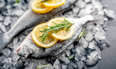 Soğuk ezilmiş buz yığını üzerinde limon dilimleri ve biberiye ile taze balık yakın görünümü