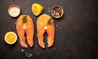 Siyah taş arka plan üzerinde baharat ve limon ile taze çiğ somon biftek