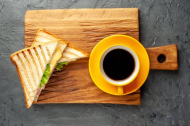 Jambon ve peynir ile taze ızgara sandviç ahşap doğrama tahtası üzerinde kahve fincan ile servis