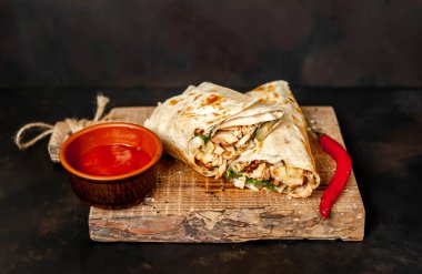 Ahşap doğrama tahtası üzerinde baharatlı sos ile tavuk ve sebze ile sarılmış geleneksel Meksika burrito 