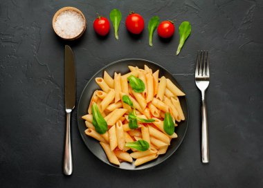 domates soslu makarna, yeşil yapraklar ve taş siyah arka plan üzerinde olgun domates