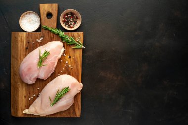 Ahşap doğrama tahtası üzerinde tuz ve biberiye dalları ile Çiğ tavuk fileto