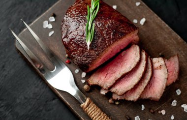 Siyah taş arka plan üzerinde baharat ve biberiye dal ile Taze ızgara biftek