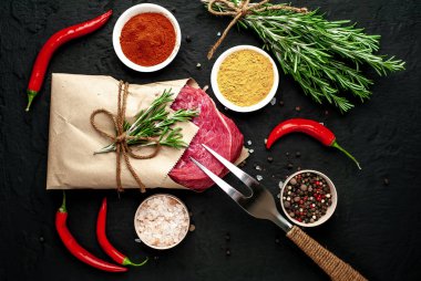Siyah taş arka plan üzerinde baharat ile Çiğ taze biftek