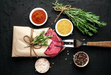 Siyah taş arka plan üzerinde baharat ile Çiğ taze biftek