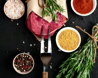 Siyah taş arka plan üzerinde baharat ile Çiğ taze biftek