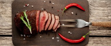 Ahşap arka planda baharat ve biberiye dalları ile taze ızgara biftek