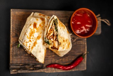 Ahşap doğrama tahtası üzerinde baharatlı sos ile tavuk ve sebze ile sarılmış geleneksel Meksika burrito 