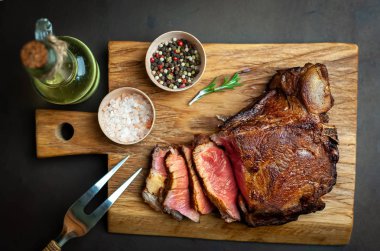 Siyah taş arka plan üzerinde ahşap doğrama tahtası üzerinde baharat ile Yağlı ızgara domuz biftek