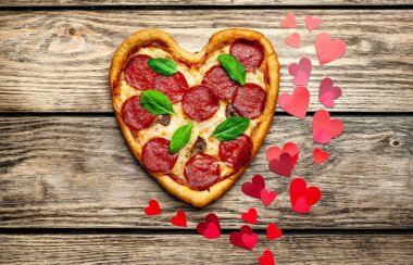 salam ve taze fesleğen yaprakları ile peynir kalp pizza kalp şekli kırmızı konfeti ile ahşap arka plan üzerinde 