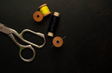 siyah arka plan üzerinde dikiş makaraları yığını ile terzi makasları 