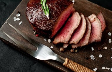 Siyah taş arka plan üzerinde baharat ve biberiye dal ile Taze ızgara biftek