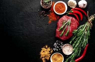 Siyah taş arka plan üzerinde baharat ile Çiğ taze biftek