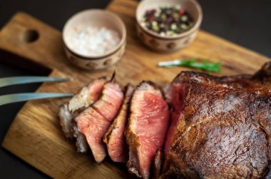 Siyah taş arka plan üzerinde ahşap doğrama tahtası üzerinde baharat ile Yağlı ızgara domuz biftek