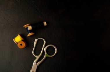 siyah arka plan üzerinde dikiş makaraları yığını ile terzi makasları 