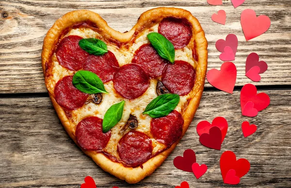 salam ve taze fesleğen yaprakları ile peynir kalp pizza kalp şekli kırmızı konfeti ile ahşap arka plan üzerinde 