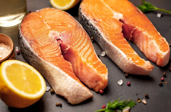 Siyah taş arka plan üzerinde baharat ve limon ile taze çiğ somon biftek