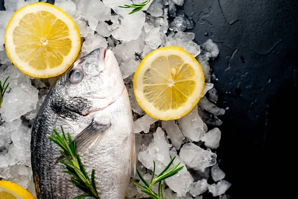 Soğuk ezilmiş buz yığını üzerinde limon dilimleri ve biberiye ile taze balık yakın görünümü