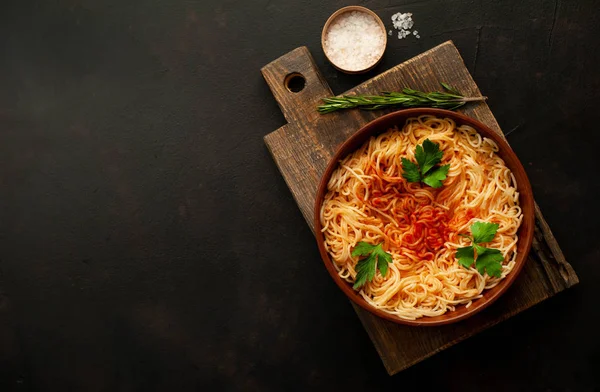 koyu taş arka plan üzerinde domates sosu ve maydanoz yaprakları ile İtalyan spagetti makarna