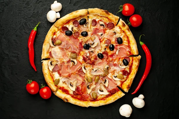 Siyah taş arka plan üzerinde mantar, domates, zeytin ve jambon ile taze ev yapımı pizza