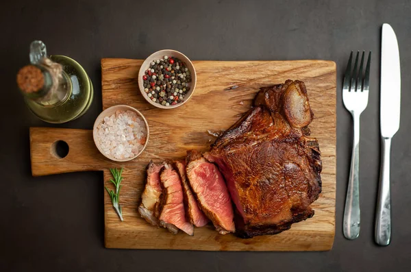 Siyah taş arka plan üzerinde ahşap doğrama tahtası üzerinde baharat ile Yağlı ızgara domuz biftek
