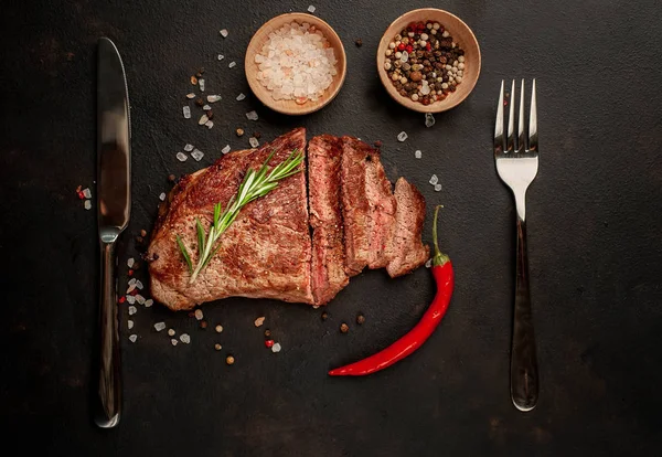 新鲜烤猪肉牛排 黑石背景上有香料和迷迭香树枝 — 图库照片
