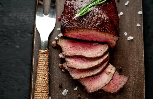 Siyah taş arka plan üzerinde baharat ve biberiye dal ile Taze ızgara biftek