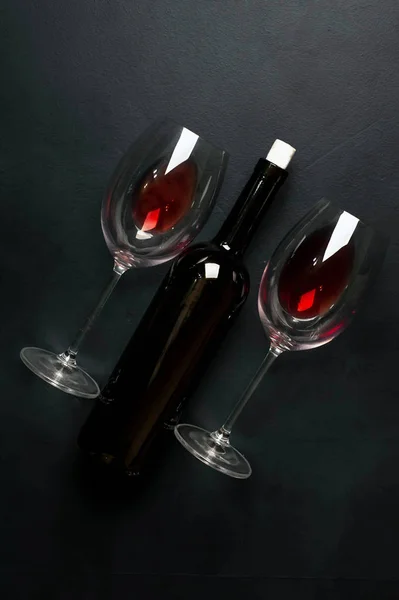 黒い背景に赤ワインとワインボトルのグラス2杯 — ストック写真