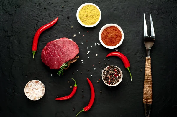 Siyah taş arka plan üzerinde baharat ile Çiğ taze biftek