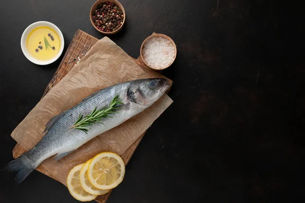 Ahşap doğrama tahtası üzerinde limon dilimleri ve biberiye dal ile çiğ balık