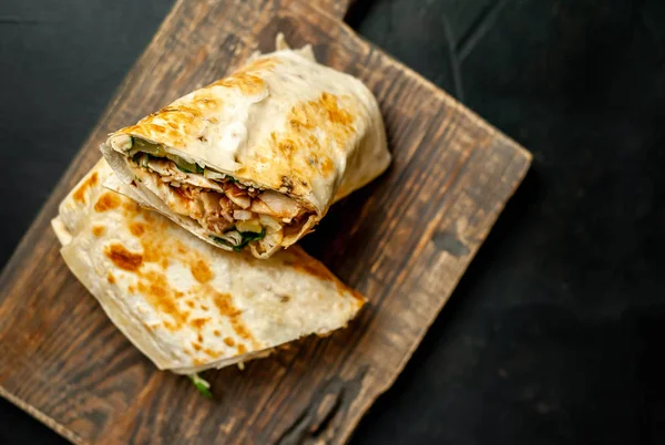 Ahşap doğrama tahtası üzerinde tavuk ve sebze ile sarılmış ev yapımı Meksika burrito 