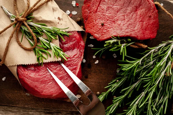 Ahşap arka plan üzerinde zanaat kağıt sarılmış baharat ile Çiğ biftek 