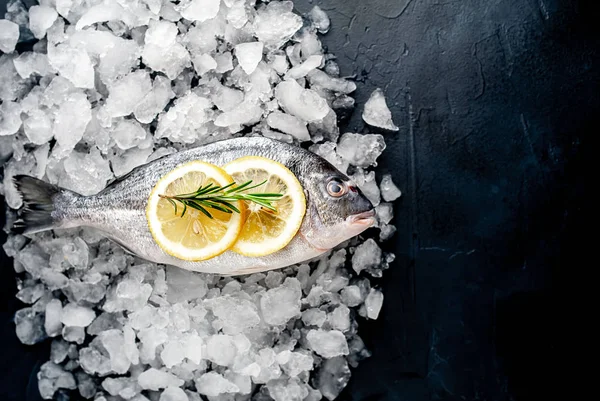 Soğuk ezilmiş buz yığını üzerinde limon dilimleri ve biberiye ile taze balık yakın görünümü
