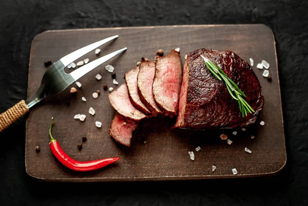 Siyah taş arka plan üzerinde baharat ve biberiye dal ile Taze ızgara biftek