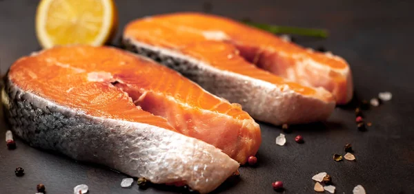 Siyah taş arka plan üzerinde baharat ve limon ile taze çiğ somon biftek