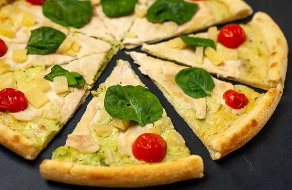 siyah taş arka plan üzerinde kiraz domates ve taze ıspanak yaprakları ile pizza