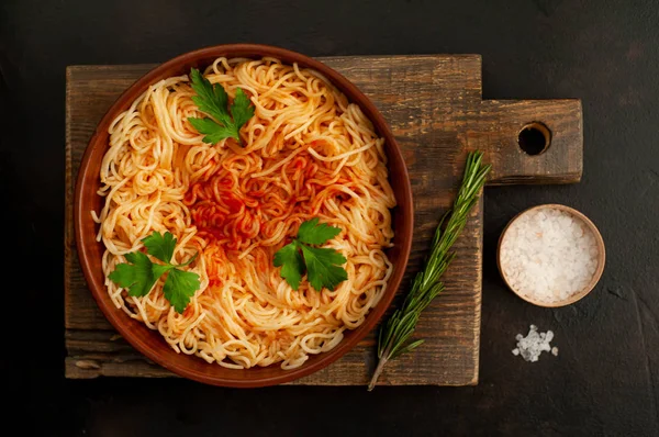 koyu taş arka plan üzerinde domates sosu ve maydanoz yaprakları ile İtalyan spagetti makarna
