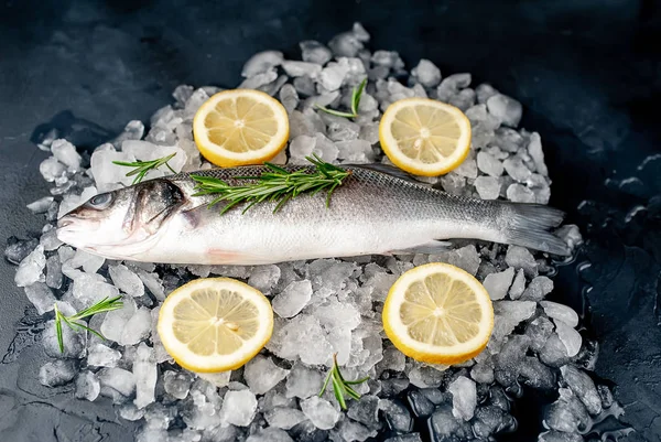 Soğuk ezilmiş buz yığını üzerinde limon dilimleri ve biberiye ile taze balık yakın görünümü