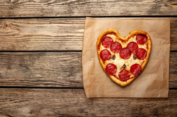 stock image cheese heart pizza with salami on wooden background