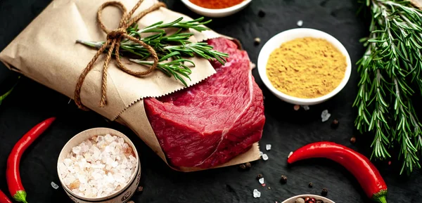Siyah taş arka plan üzerinde baharat ile Çiğ taze biftek