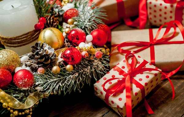 Pile of gift boxes with red bows and fir wreath with decor on old wooden background