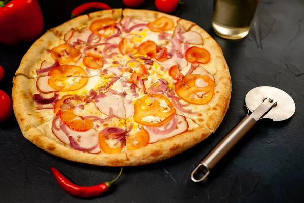 Fresh vegetable pizza with ham on black stone background