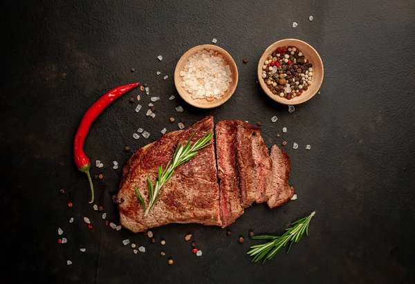 Siyah taş arka plan üzerinde baharat ve biberiye dalları ile Taze ızgara domuz biftek