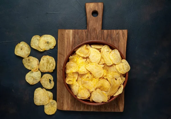 Siyah taş arka plan üzerinde gevrek tuzlu patates cips