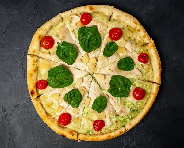 siyah taş arka plan üzerinde kiraz domates ve taze ıspanak yaprakları ile pizza