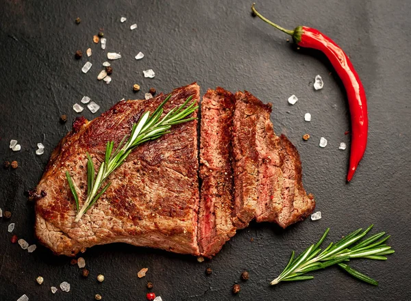 Siyah taş arka plan üzerinde baharat ve biberiye dalları ile Taze ızgara domuz biftek