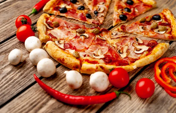 Ahşap arka plan üzerinde mantar, domates, zeytin ve jambon ile taze ev yapımı pizza