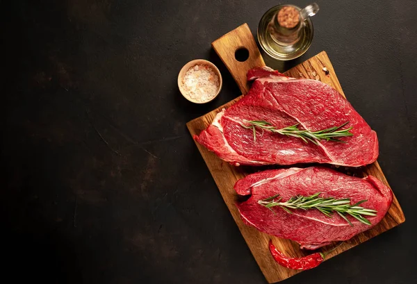 Taş arka planda baharat ve biberiye ile çiğ sığır biftek